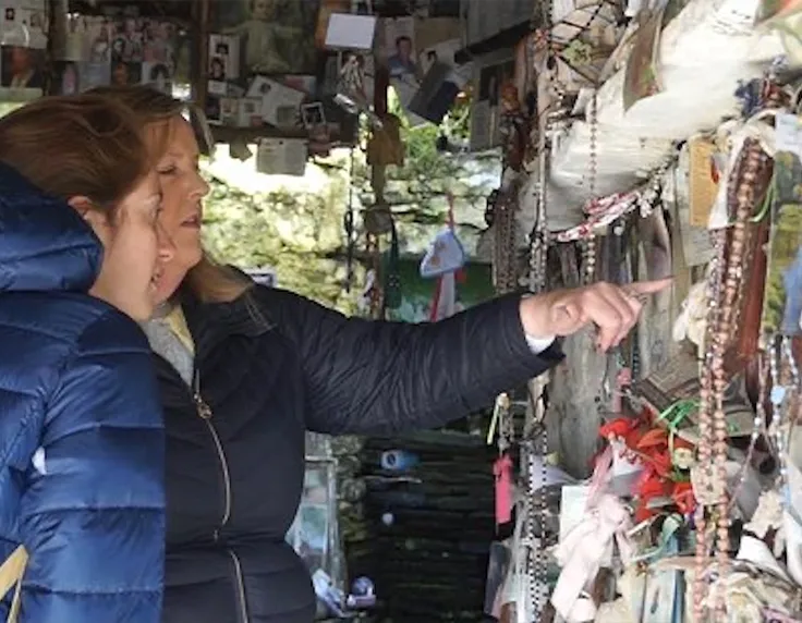 A tour being shown how to make a straw cross for St. Brigid