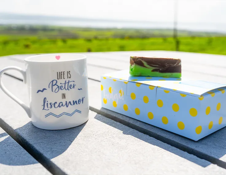 Moher Cottage fudge and coffee cup on table with view of countryside in background