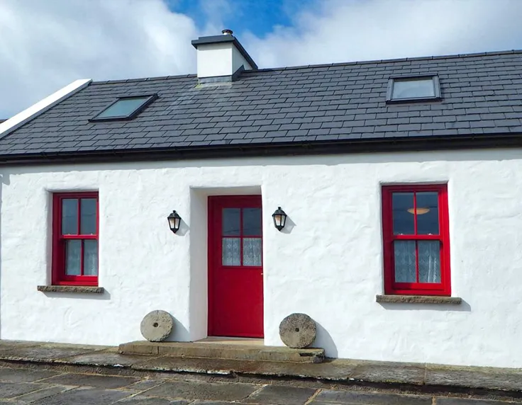 White cottage with red accents on door and windows